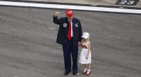 Donald Trump waves to NASCAR fans as he holds the hand of granddaughter Carolina