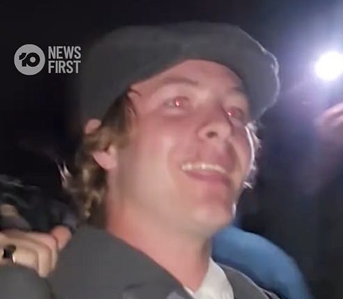 The smiling heckler is pictured being escorted from a dawn service in Melbourne where he interrupted a Welcome to Country to protest: 'Australia is for the white man'