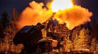 A muzzle flash lights up pine trees as the British Army's Archer Mobile Howitzer gun fires during training near Rovaniemi in the Arctic Circle, Finland, in November