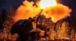 A muzzle flash lights up pine trees as the British Army's Archer Mobile Howitzer gun fires during training near Rovaniemi in the Arctic Circle, Finland, in November