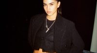 Woman in black cardigan and jeans at night.