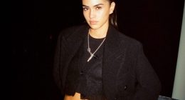 Woman in black cardigan and jeans at night.