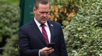 National Security Adviser Michael Waltz looks at his phone as he prepares for a TV interview at the White House on Thursday immediately before his firing