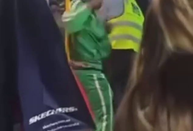 The bus driver appeared to be punched in the face by the man in the green jumpsuit (pictured)