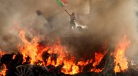 Images of the violence showse a man waving a Mexican flag as flames rise from a burning Waymo
