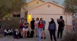 Protesters demonstrating against a drug bust outside a house.