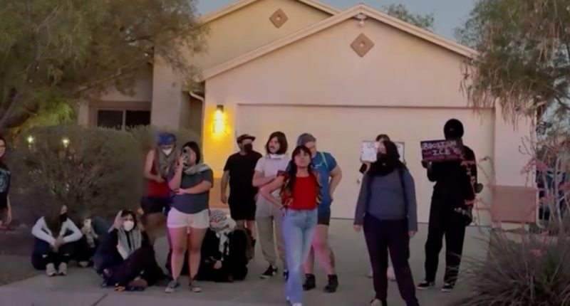 Protesters demonstrating against a drug bust outside a house.