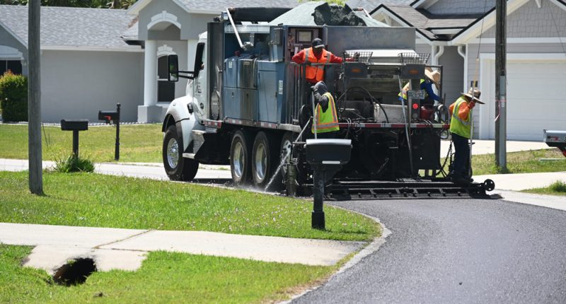 A crew applying an asphalt sealant on a P-Section street in April. The sealant is a lower-grade, cheaper alternative to repaving. It is intended to extend the life of a street