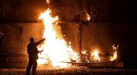 A firefighter stands by a fire and points to a hole following a drone strike in Kharkiv on June 5
