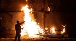 A firefighter stands by a fire and points to a hole following a drone strike in Kharkiv on June 5