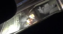 Pictured is the moment a female officer ducked for cover after a large stone was lobbed at the windshield of a parked police vehicle