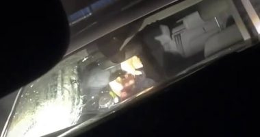 Pictured is the moment a female officer ducked for cover after a large stone was lobbed at the windshield of a parked police vehicle