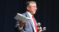 Mike Norris with a copy of the ethics complaint against him as he addressed his town hall crowd about it on Monday, saying it had been dismissed. (© FlaglerLive)