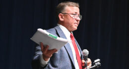 Mike Norris with a copy of the ethics complaint against him as he addressed his town hall crowd about it on Monday, saying it had been dismissed. (© FlaglerLive)