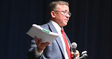 Mike Norris with a copy of the ethics complaint against him as he addressed his town hall crowd about it on Monday, saying it had been dismissed. (© FlaglerLive)