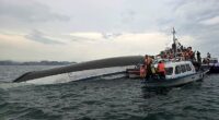 Relief personnel gathered around a capsized tourist boat, which had been carrying 53 passengers when it capsized - of these at least 27 are believed to have died