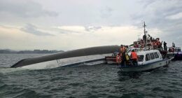 Relief personnel gathered around a capsized tourist boat, which had been carrying 53 passengers when it capsized - of these at least 27 are believed to have died